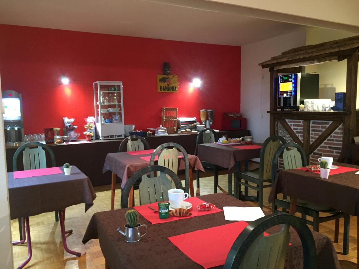 un restaurant avec des tables et des chaises aux murs rouges dans l'établissement Le Pavillon, à Cours-la-Ville