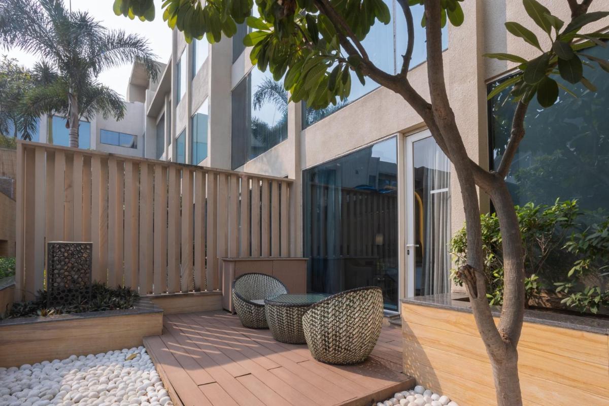 a patio with chairs and a tree in front of a building at InterContinental Jaipur Tonk Road by IHG in Jaipur