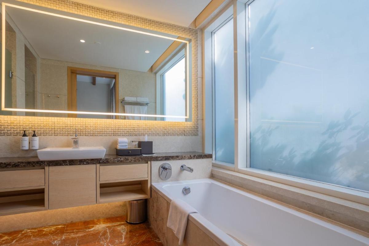 a bathroom with a tub and a sink and a large window at InterContinental Jaipur Tonk Road by IHG in Jaipur
