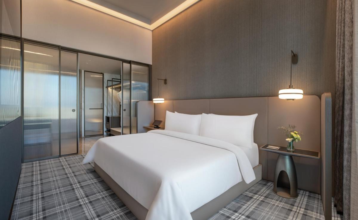 a bedroom with a large white bed and glass walls at The Residency Towers in Chennai
