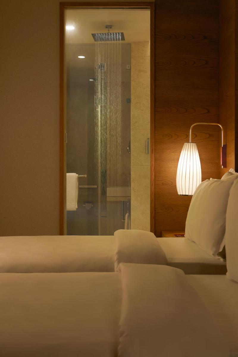 a bedroom with a bed and a lamp and a mirror at The Residency Towers in Chennai
