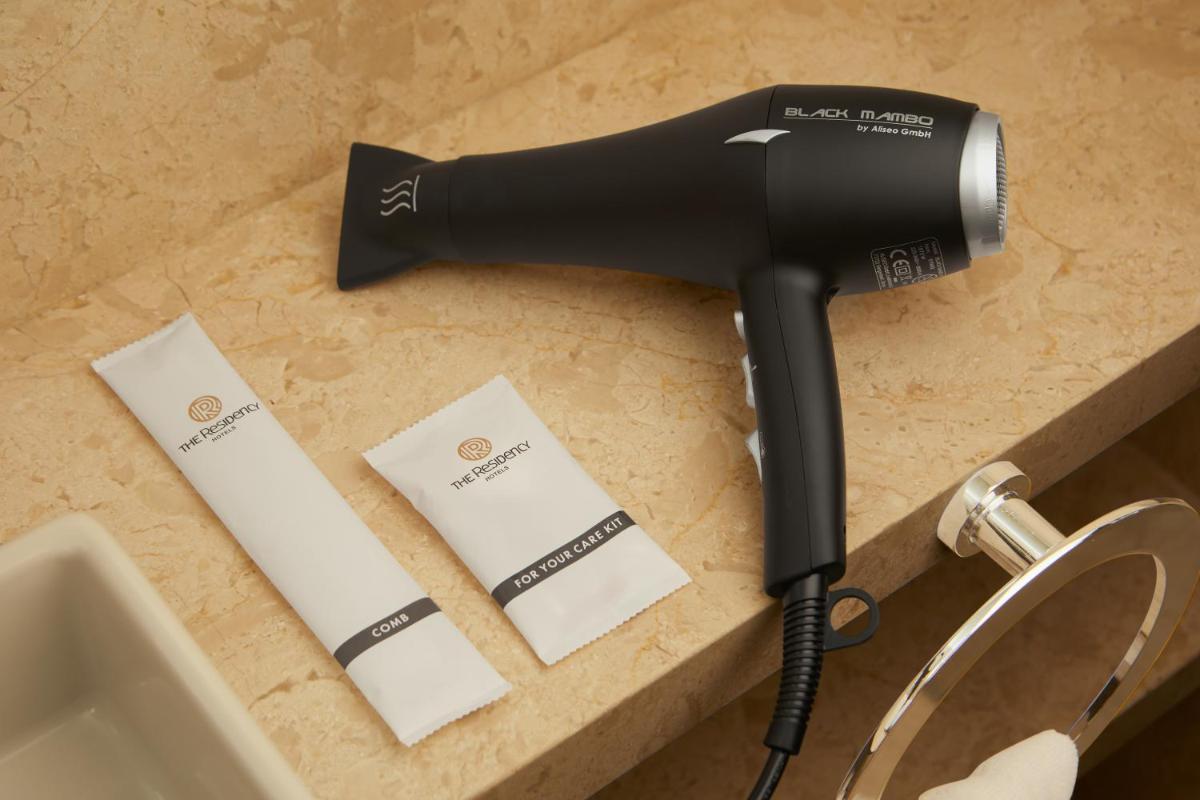 a hair dryer on a counter next to a sink at The Residency Towers in Chennai