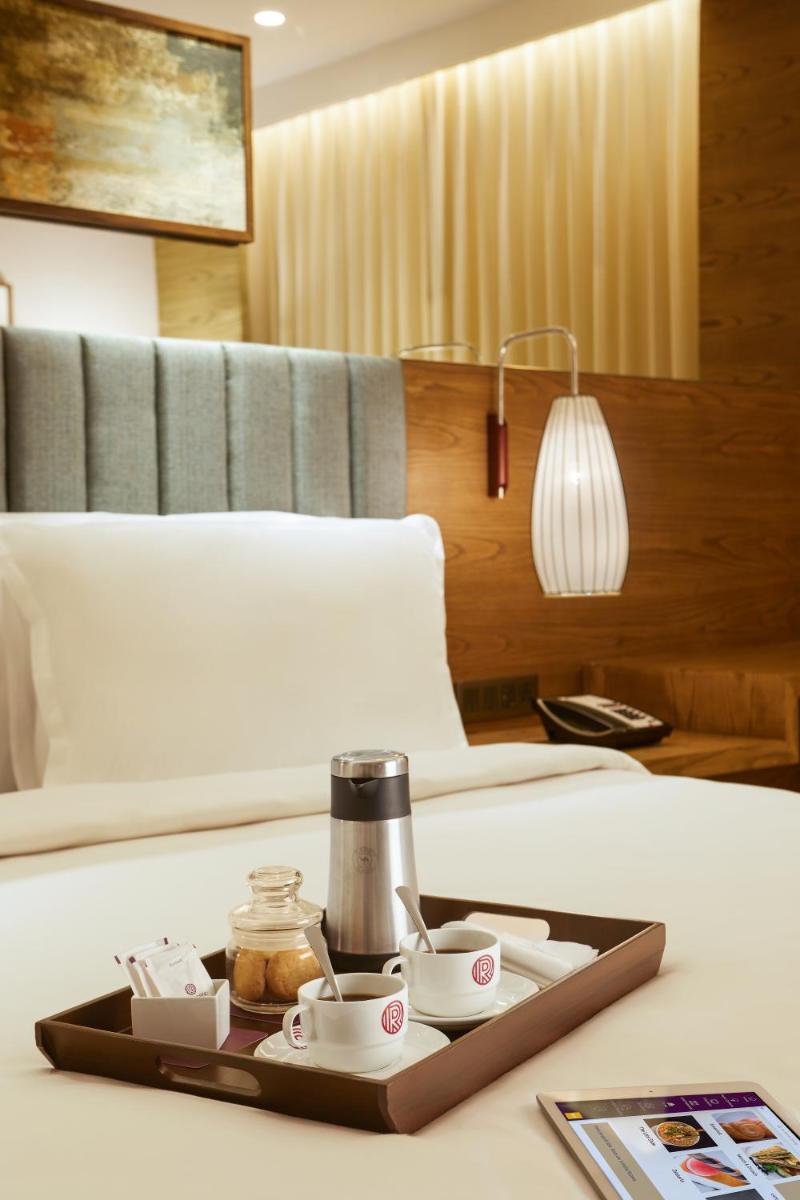 a tray with cups and teaiments on a bed at The Residency Towers in Chennai