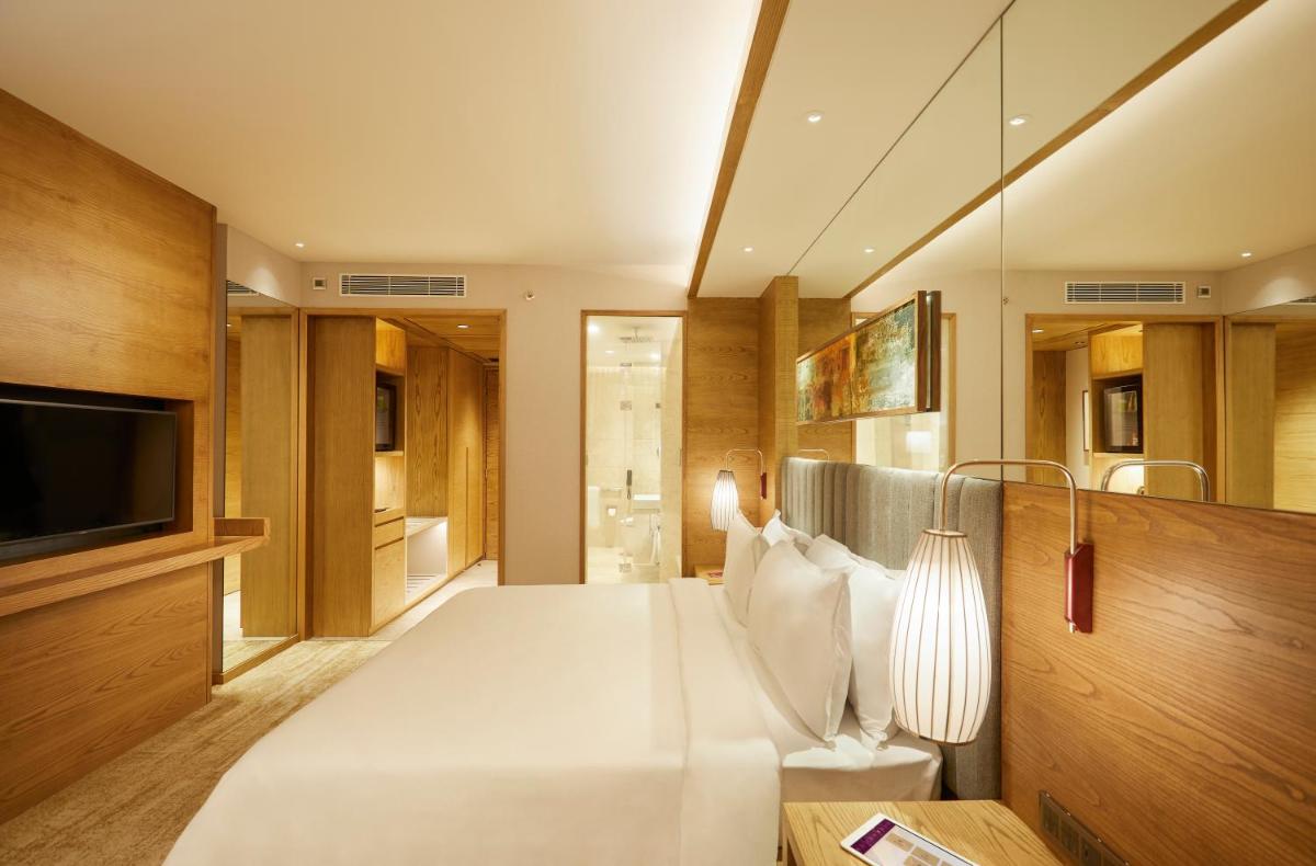 a bedroom with a large white bed and a television at The Residency Towers in Chennai