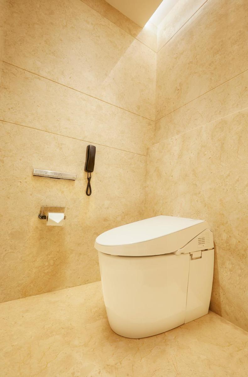 a bathroom with a toilet and a phone on the wall at The Residency Towers in Chennai