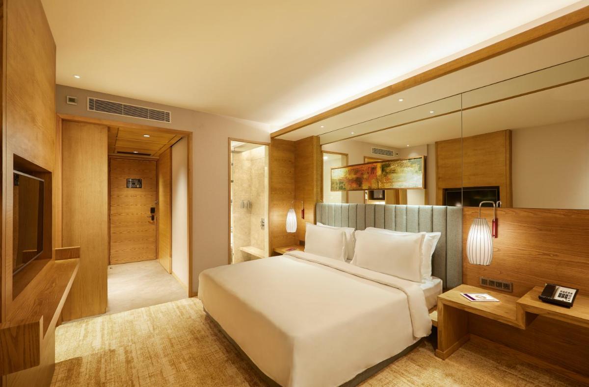 a bedroom with a white bed and a walk in shower at The Residency Towers in Chennai