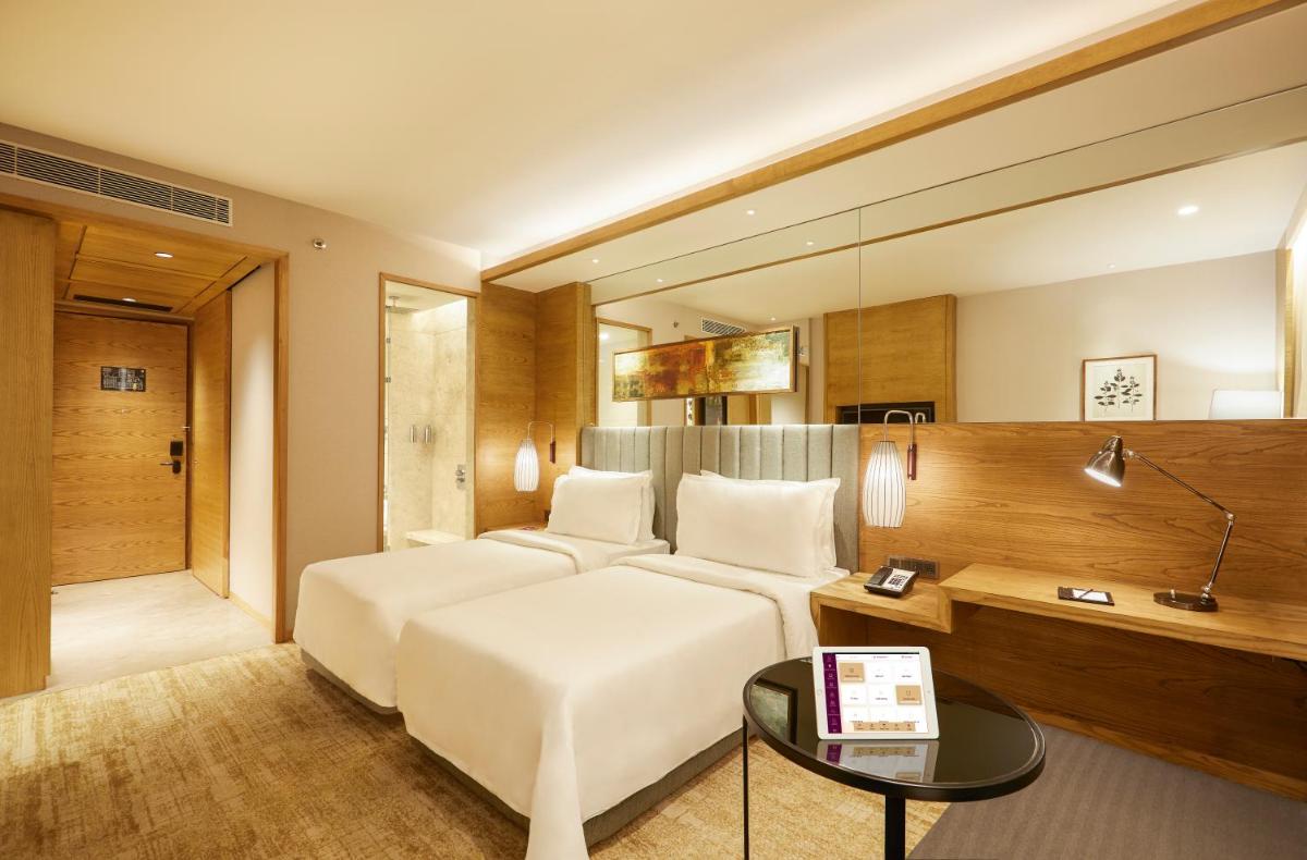 a hotel room with a white bed and a table at The Residency Towers in Chennai