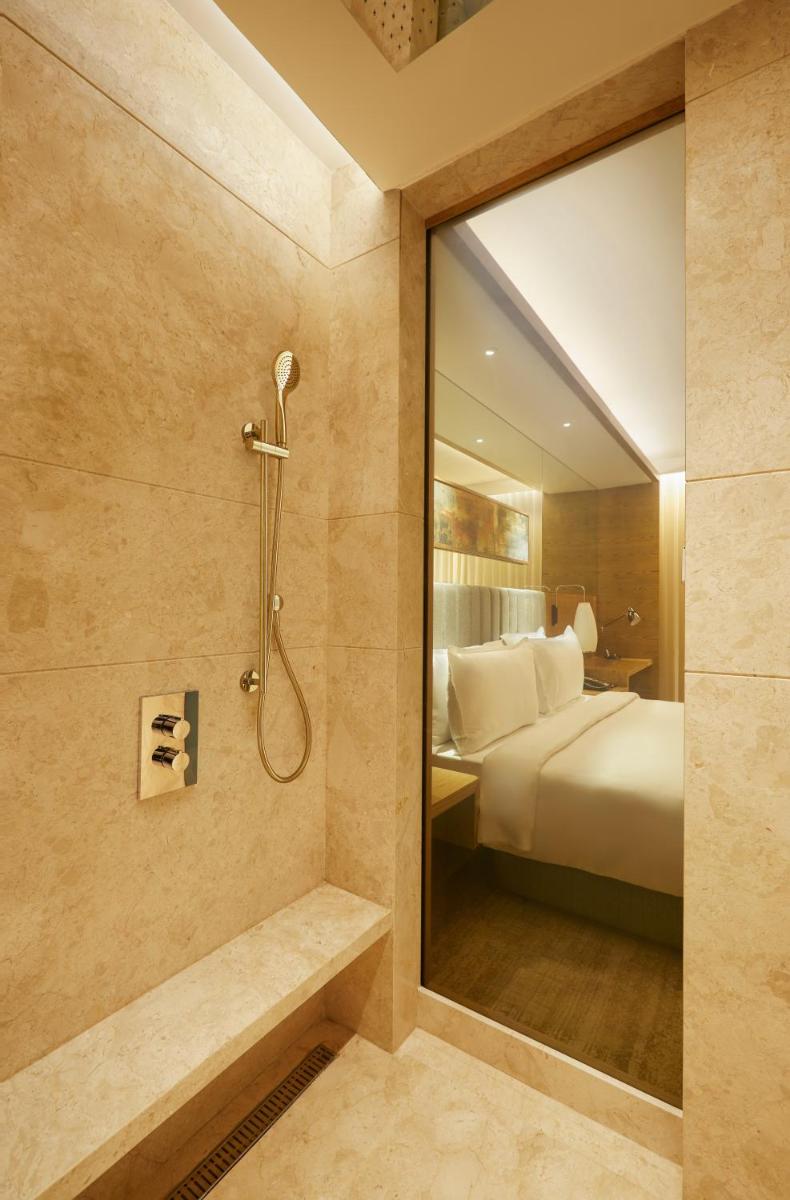 a bathroom with a shower and a bed and a mirror at The Residency Towers in Chennai