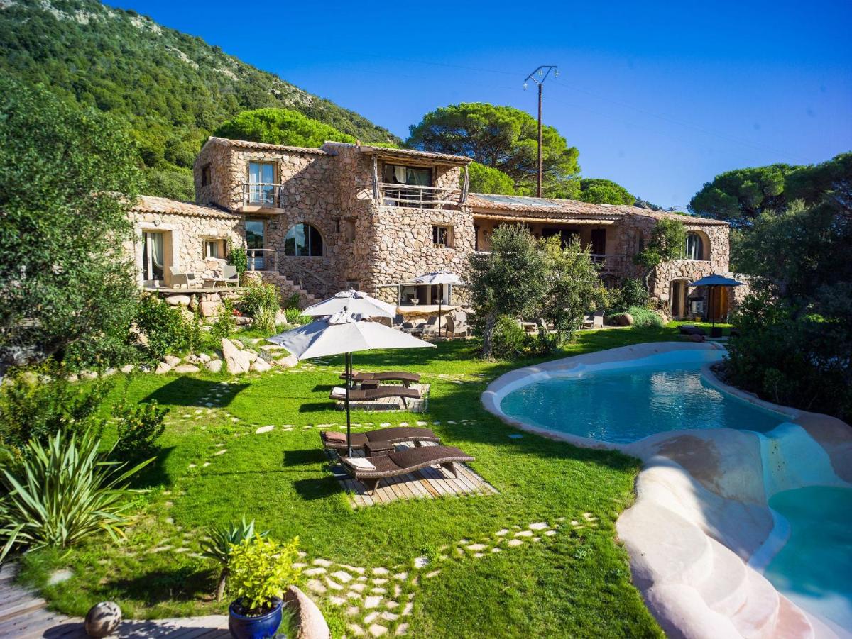 une maison en pierre avec une piscine dans la cour dans l'établissement Hôtel Ambassador Palombaggia, à Porto-Vecchio