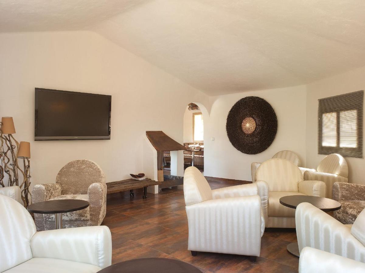 d'un salon avec des chaises blanches et une télévision à écran plat. dans l'établissement Hôtel Ambassador Palombaggia, à Porto-Vecchio