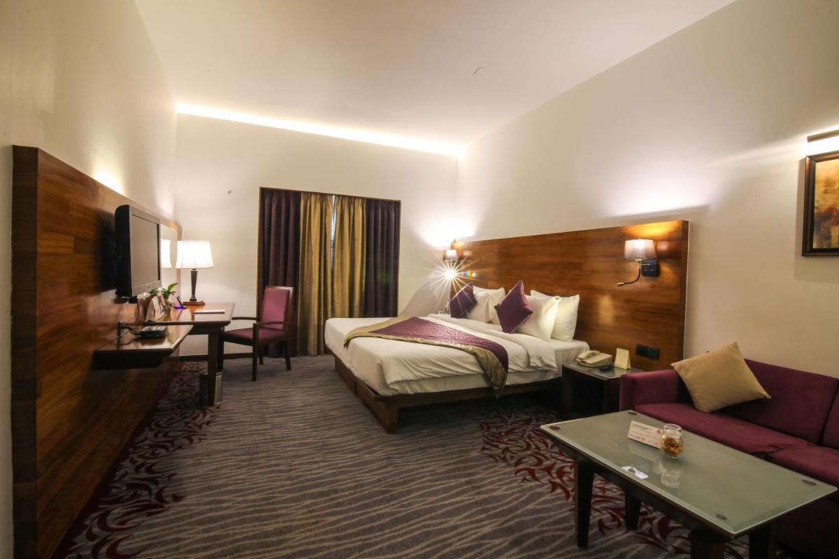 a hotel room with a bed and a couch at The Orchid Hotel Hinjewadi Pune in Pune a hotel room with a bed and a couch at The Orchid Hotel Hinjewadi Pune in Pune