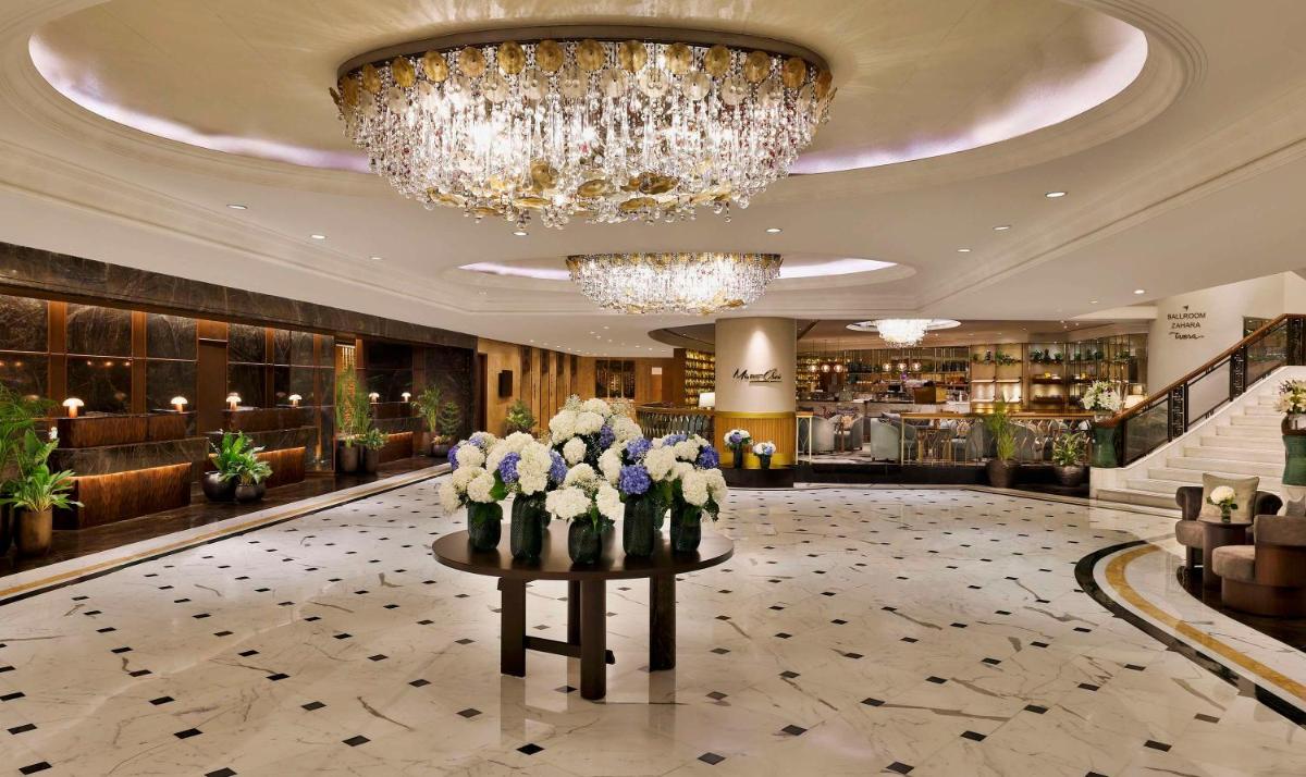 a lobby with a chandelier and flowers on a table at Shangri-La Eros New Delhi in New Delhi a lobby with a chandelier and flowers on a table at Shangri-La Eros New Delhi in New Delhi