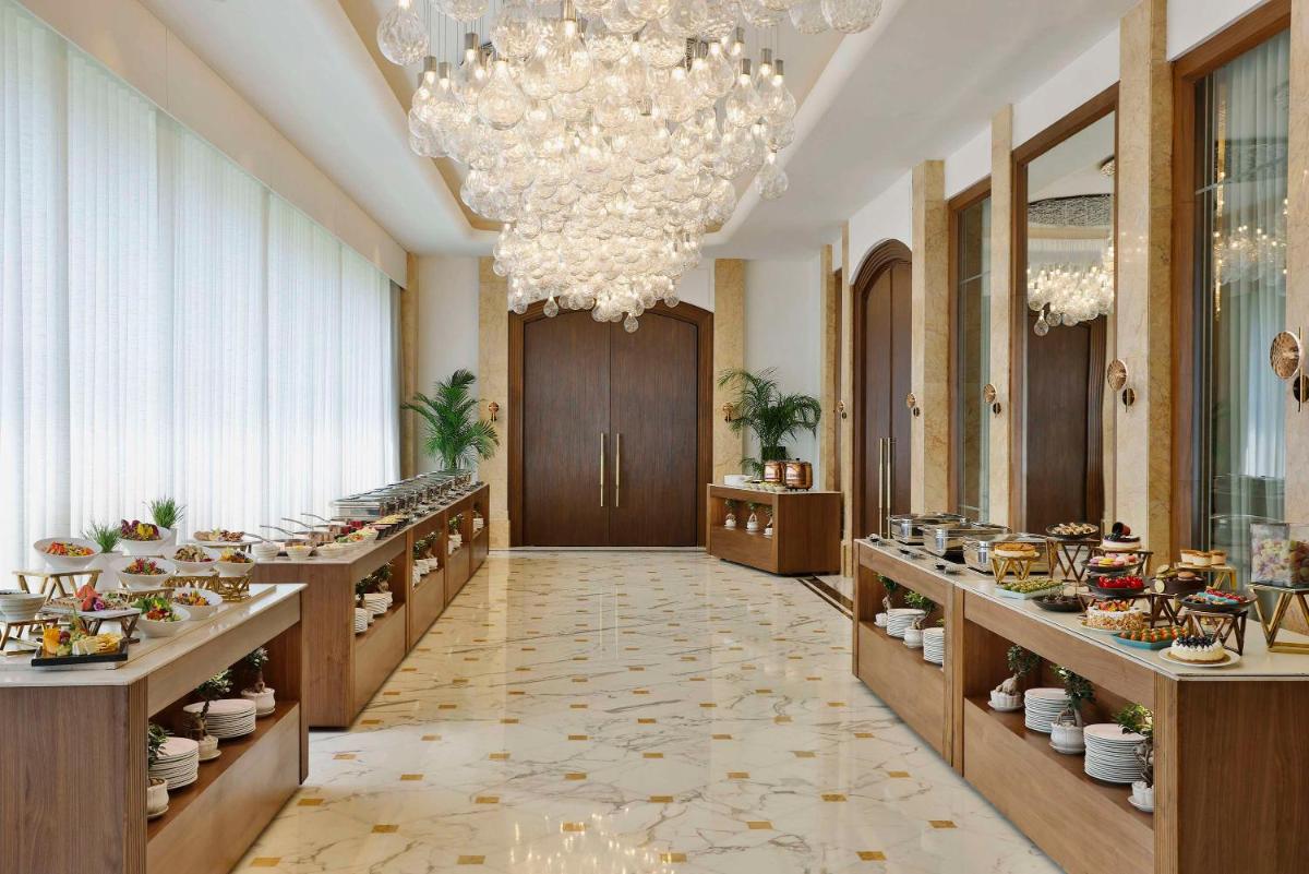 a hallway with a buffet line with food on display at Shangri-La Eros New Delhi in New Delhi a hallway with a buffet line with food on display at Shangri-La Eros New Delhi in New Delhi