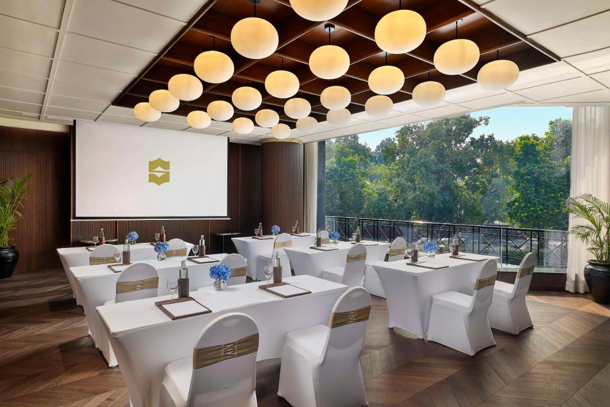 a conference room with white tables and chairs and a screen at Shangri-La Eros New Delhi in New Delhi a conference room with white tables and chairs and a screen at Shangri-La Eros New Delhi in New Delhi