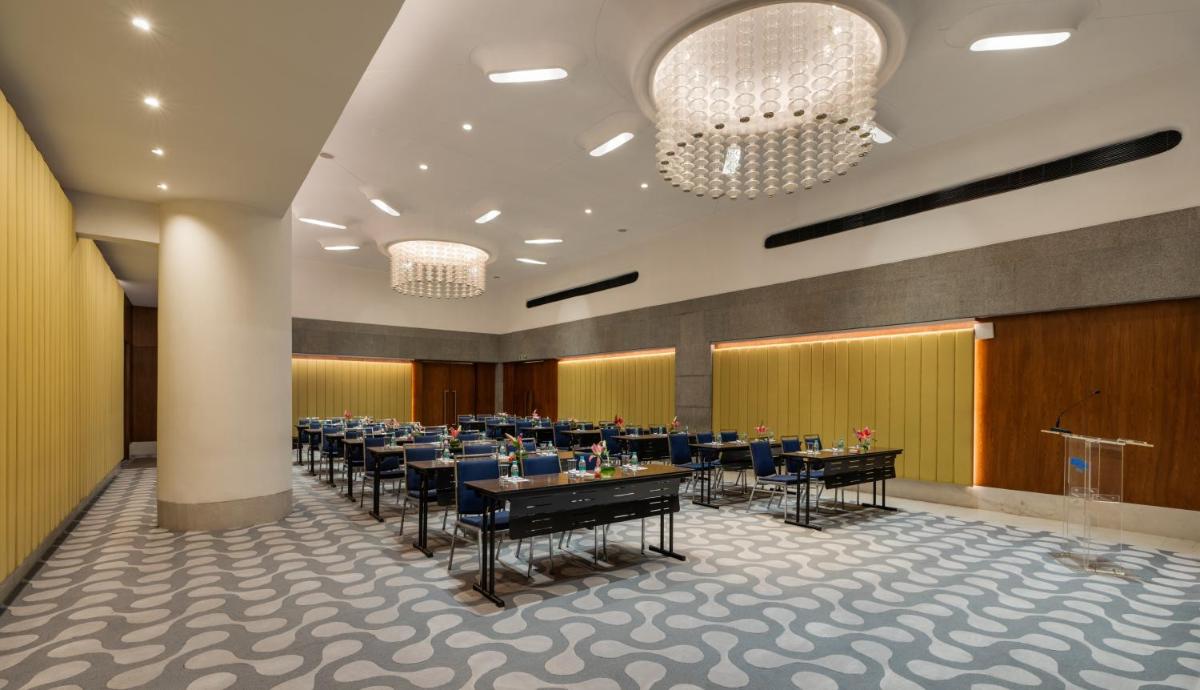 a banquet hall with tables and chairs and a chandelier at Avasa Hotel in Hyderabad