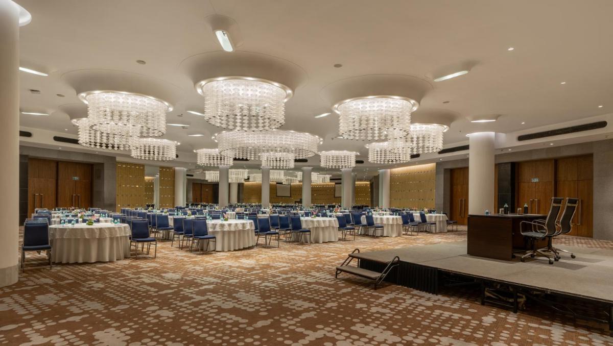 a banquet hall with tables and chairs and chandeliers at Avasa Hotel in Hyderabad