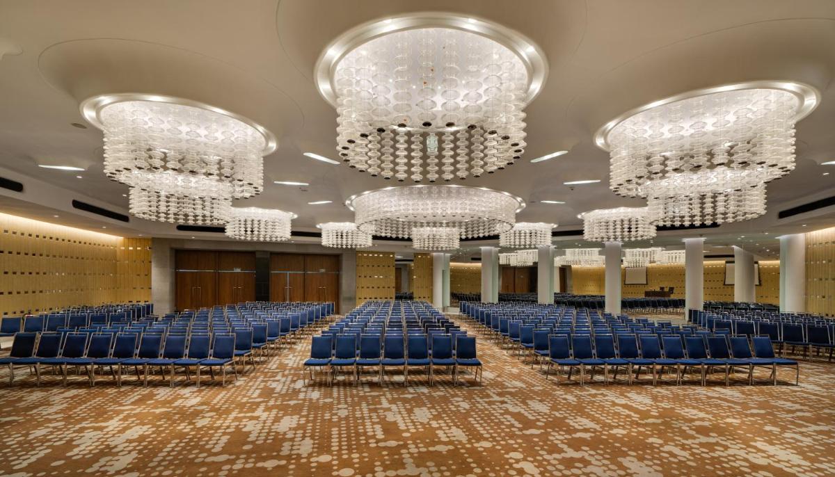 a banquet hall with blue chairs and chandeliers at Avasa Hotel in Hyderabad