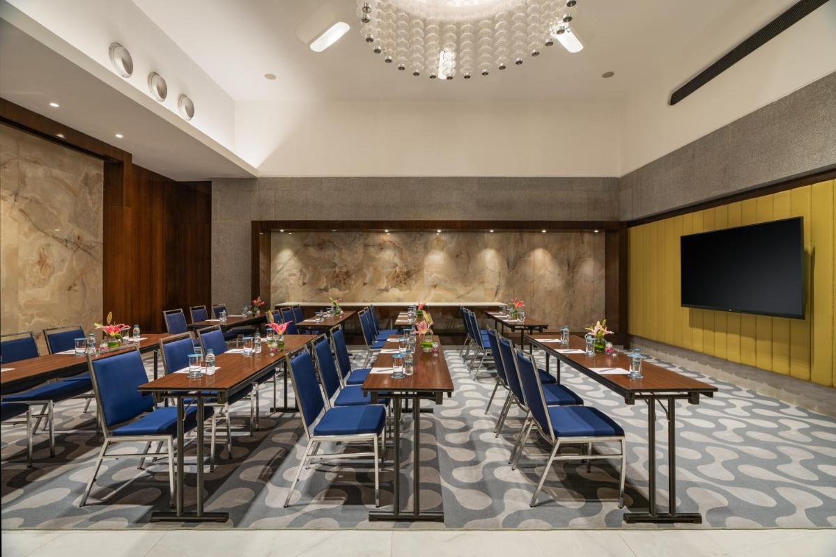 a dining room with tables and chairs and a flat screen tv at Avasa Hotel in Hyderabad