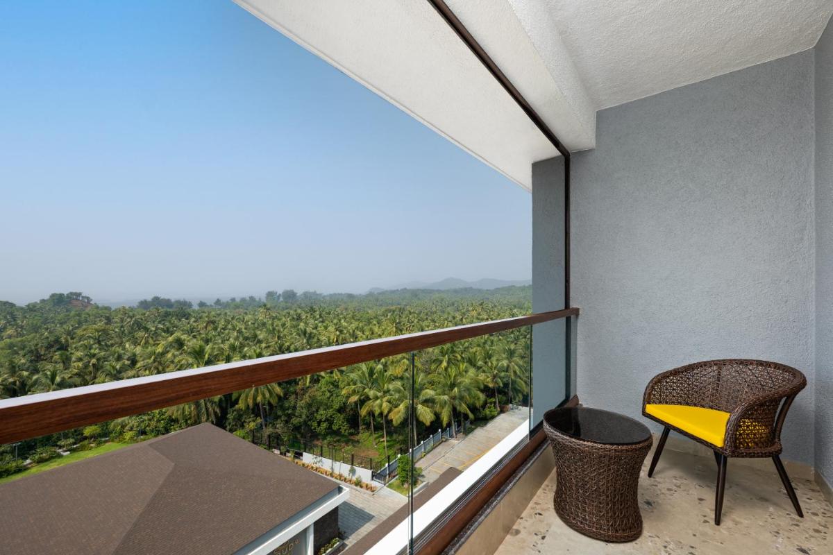 a balcony with a yellow chair and a view of a forest at Gateway Goa, Palolem in Palolem