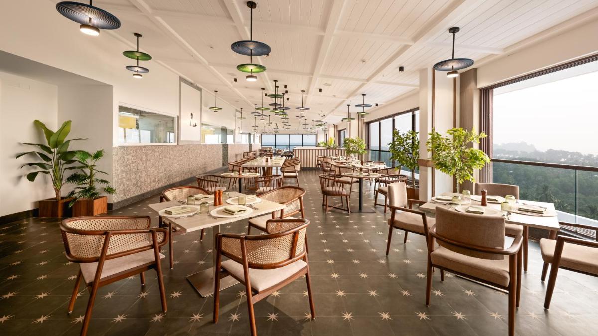 a restaurant with tables and chairs and large windows at Gateway Goa, Palolem in Palolem
