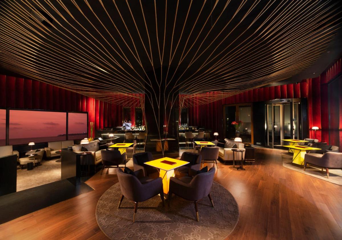a lobby with tables and chairs and a tree at The Oberoi Mumbai in Mumbai