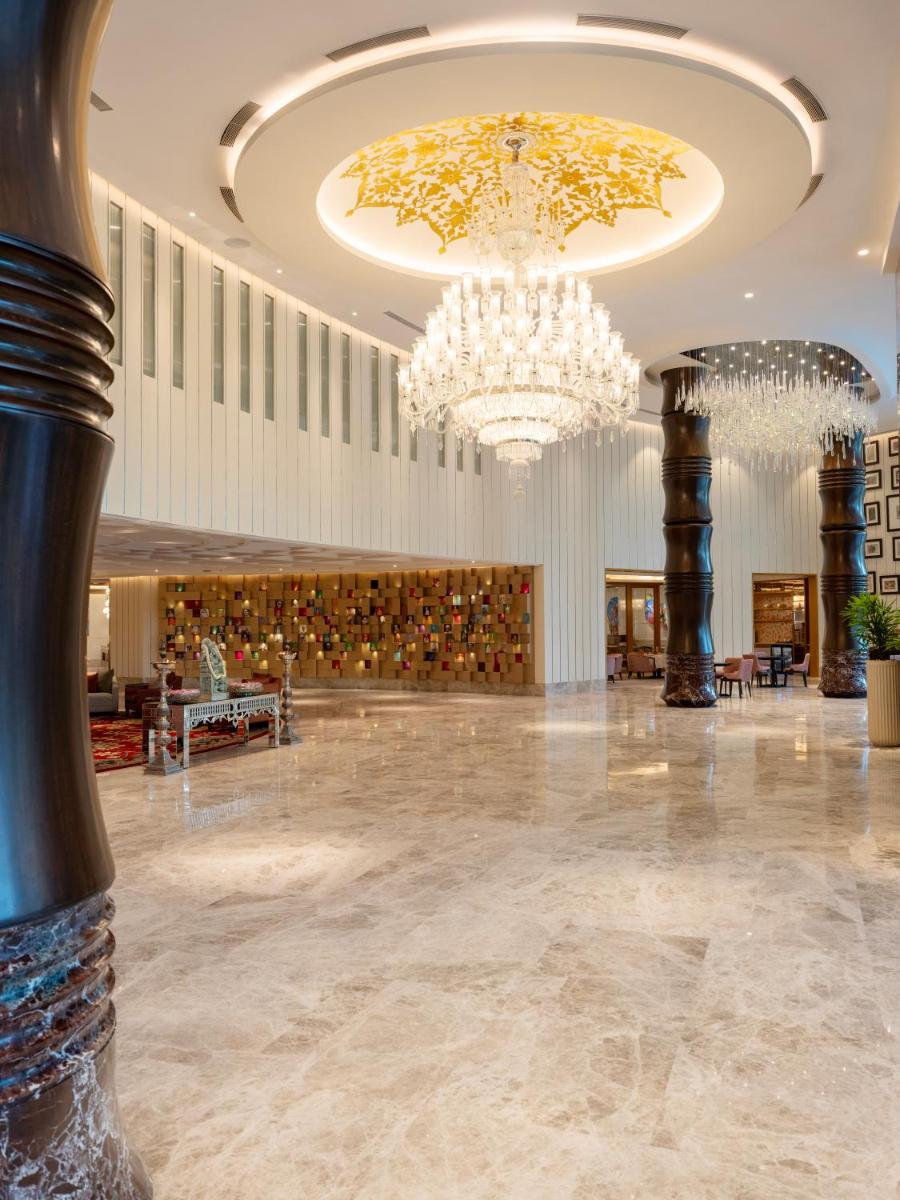 a lobby with a chandelier and a large room at The Leela Hyderabad Banjara Hills in Hyderabad
