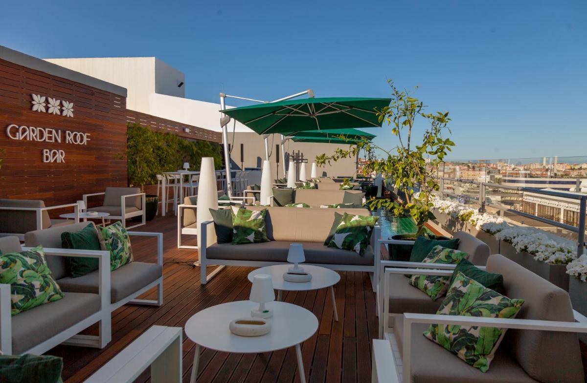 um pátio no último piso com sofás e mesas num edifício em Altis Grand Hotel em Lisboa