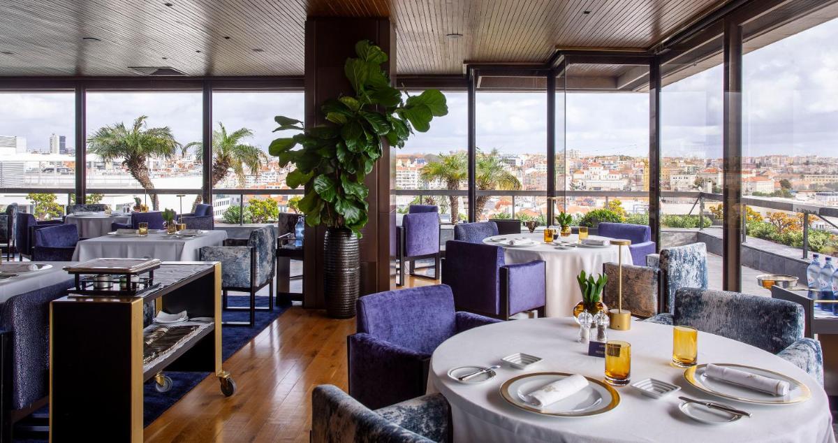um restaurante com mesas e cadeiras com vista para a cidade em Altis Grand Hotel em Lisboa