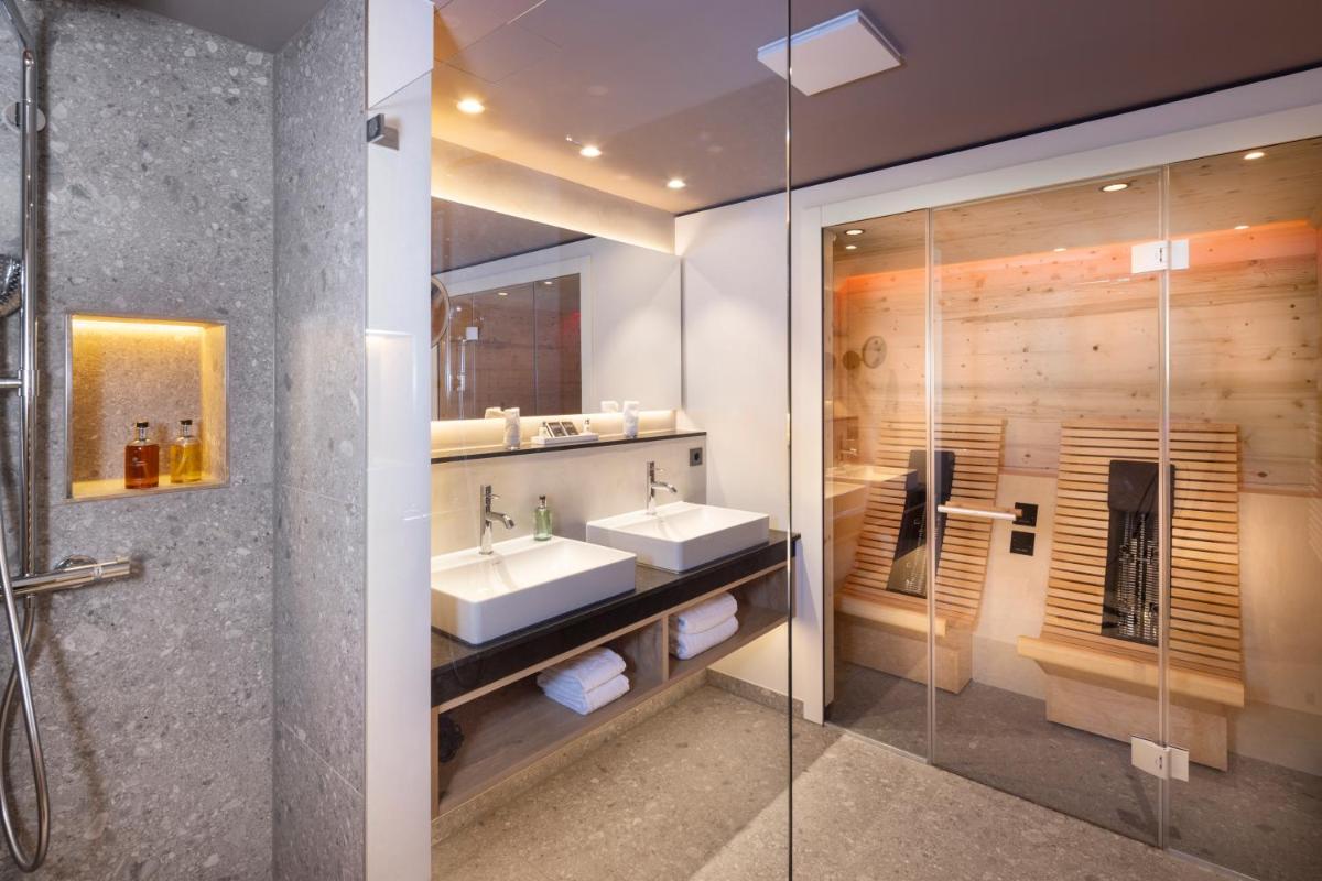 ein Badezimmer mit zwei Waschbecken und einer Glasdusche in der Unterkunft Wellness & Genuss Resort - Engel Obertal in Baiersbronn