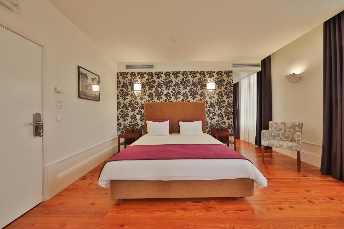 um quarto com uma cama grande e uma cadeira em Hotel Quinta da Cruz & SPA em Ataíde mais 66 fotografias