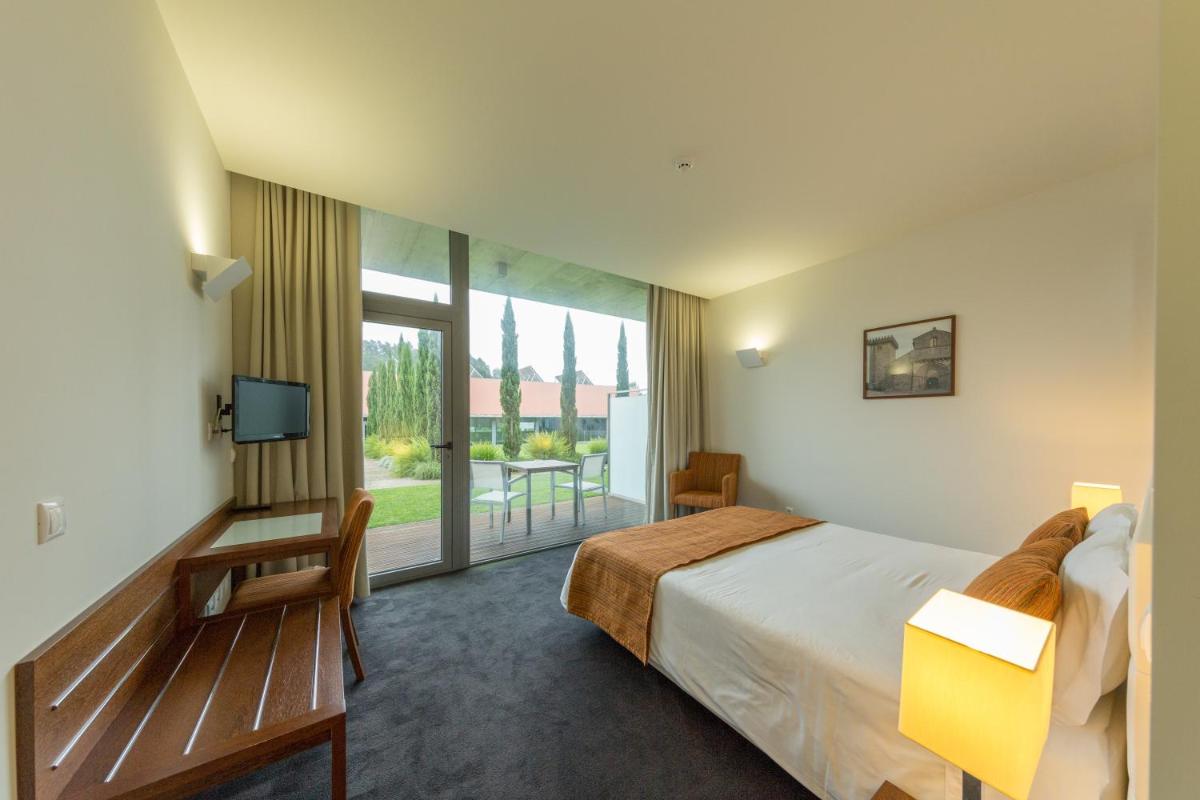um quarto de hotel com uma cama e uma varanda em Hotel Quinta da Cruz & SPA em Ataíde