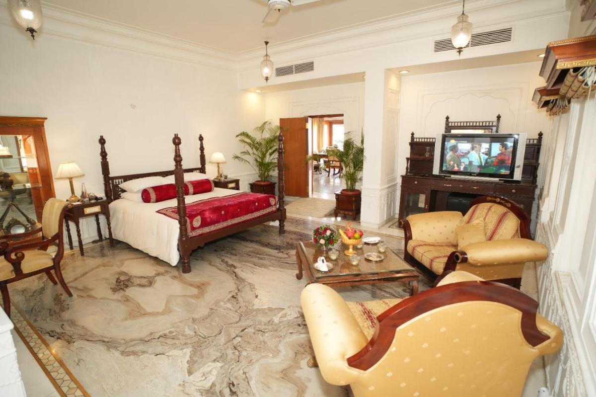 a living room with a bed and a tv at The Raj Palace (Small Luxury Hotels of the World) in Jaipur