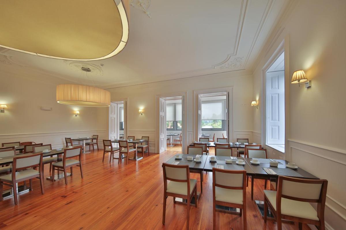um quarto amplo com mesas e cadeiras de madeira em Hotel Quinta da Cruz & SPA em Ataíde