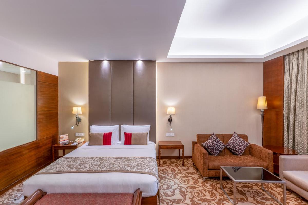 a hotel room with two beds and a couch at Pride Plaza Hotel, Kolkata in Kolkata