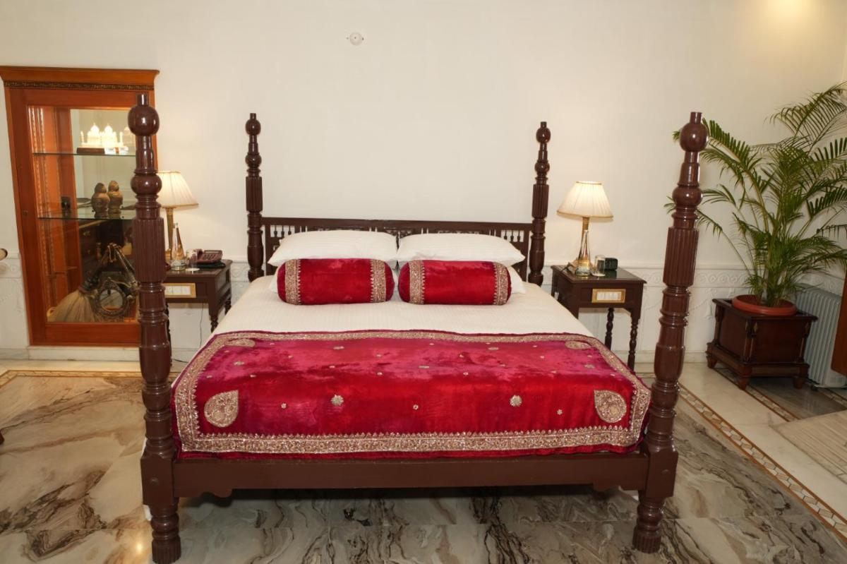 a bedroom with a bed with two red pillows at The Raj Palace (Small Luxury Hotels of the World) in Jaipur