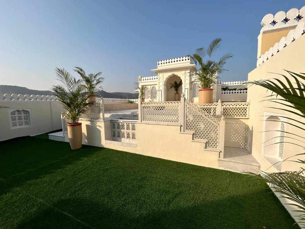 a white house with a yard with green grass at The Raj Palace (Small Luxury Hotels of the World) in Jaipur