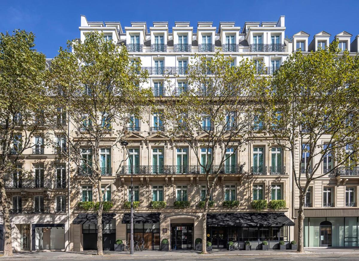 un grand bâtiment avec des arbres devant dans l'établissement Hyatt Paris Madeleine, à Paris