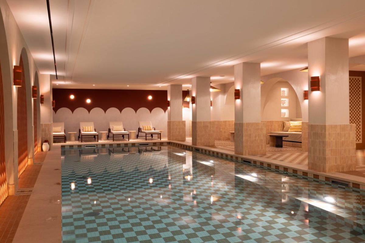 - une grande piscine dans un hôtel avec des chaises et des tables dans l'établissement Hotel Grand Coeur Latin, à Paris