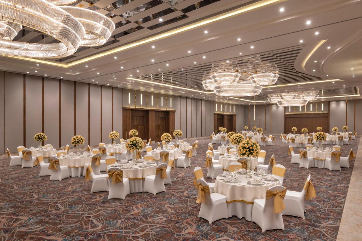a banquet hall with white tables and chairs and chandeliers at Welcomhotel by ITC Hotels, Delhi-Gurugram Highway in New Delhi