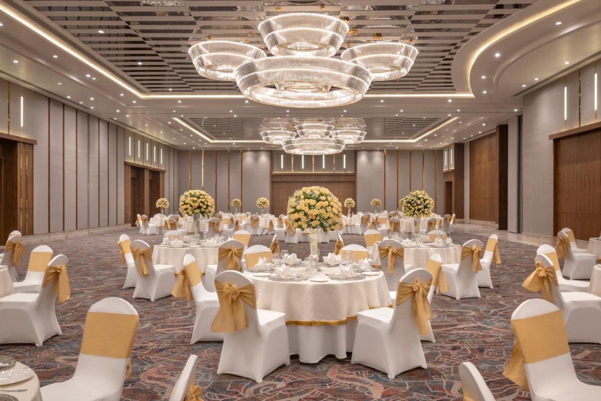 a banquet hall with white tables and chairs and a chandelier at Welcomhotel by ITC Hotels, Delhi-Gurugram Highway in New Delhi