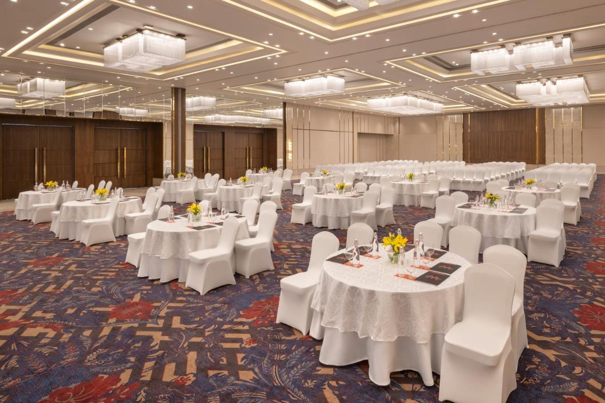 a banquet hall with white tables and white chairs at Welcomhotel by ITC Hotels, Delhi-Gurugram Highway in New Delhi