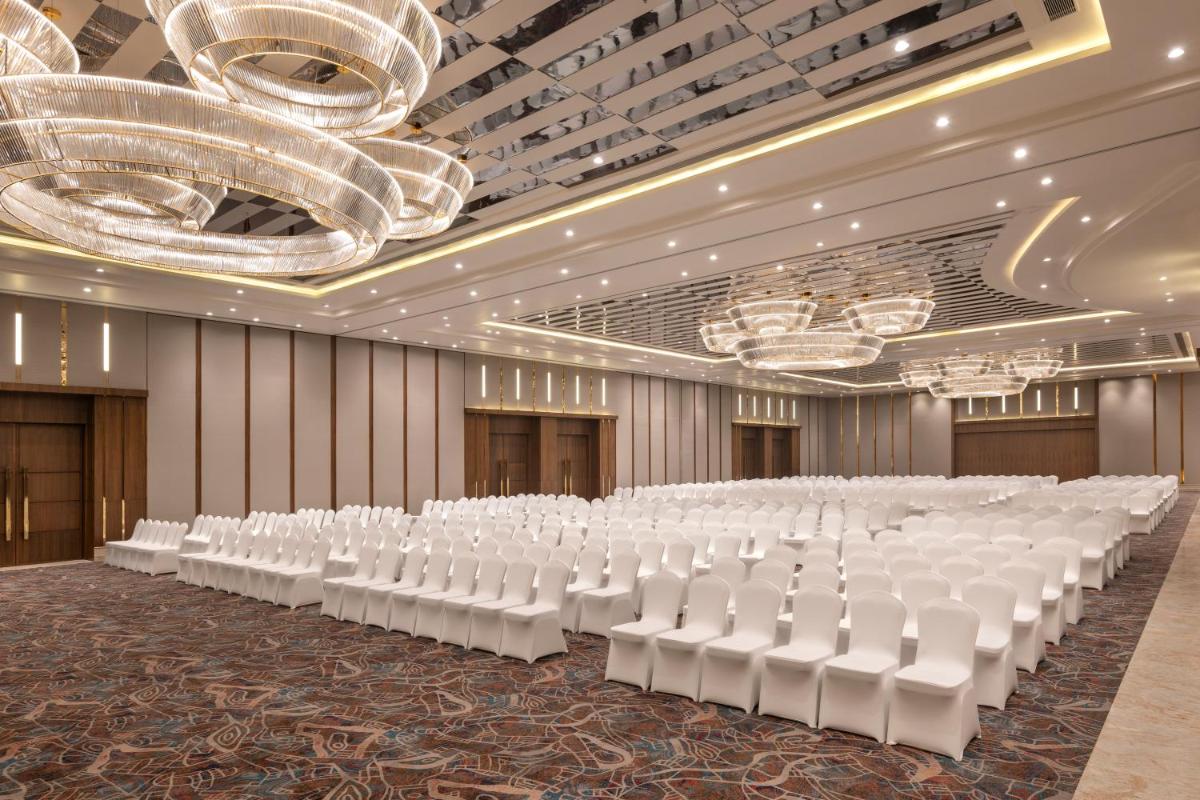 an empty banquet hall with white chairs and a stage at Welcomhotel by ITC Hotels, Delhi-Gurugram Highway in New Delhi