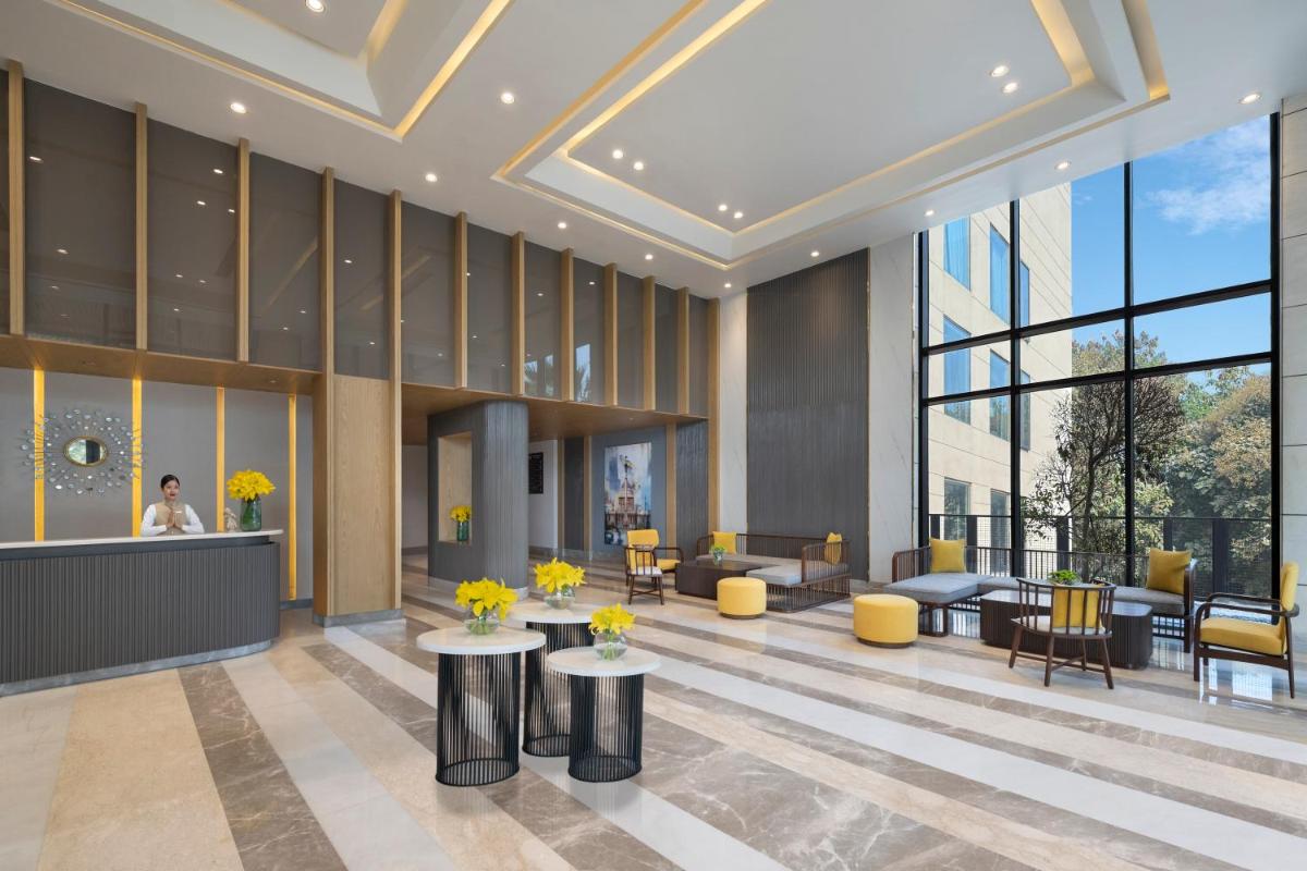 a lobby of a building with tables and chairs at Welcomhotel by ITC Hotels, Delhi-Gurugram Highway in New Delhi