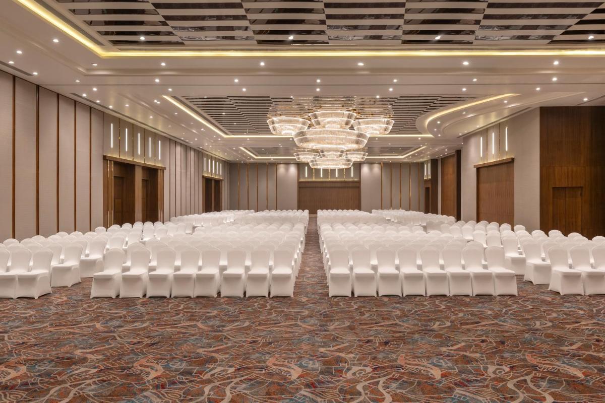 a banquet hall with rows of white chairs and a chandelier at Welcomhotel by ITC Hotels, Delhi-Gurugram Highway in New Delhi