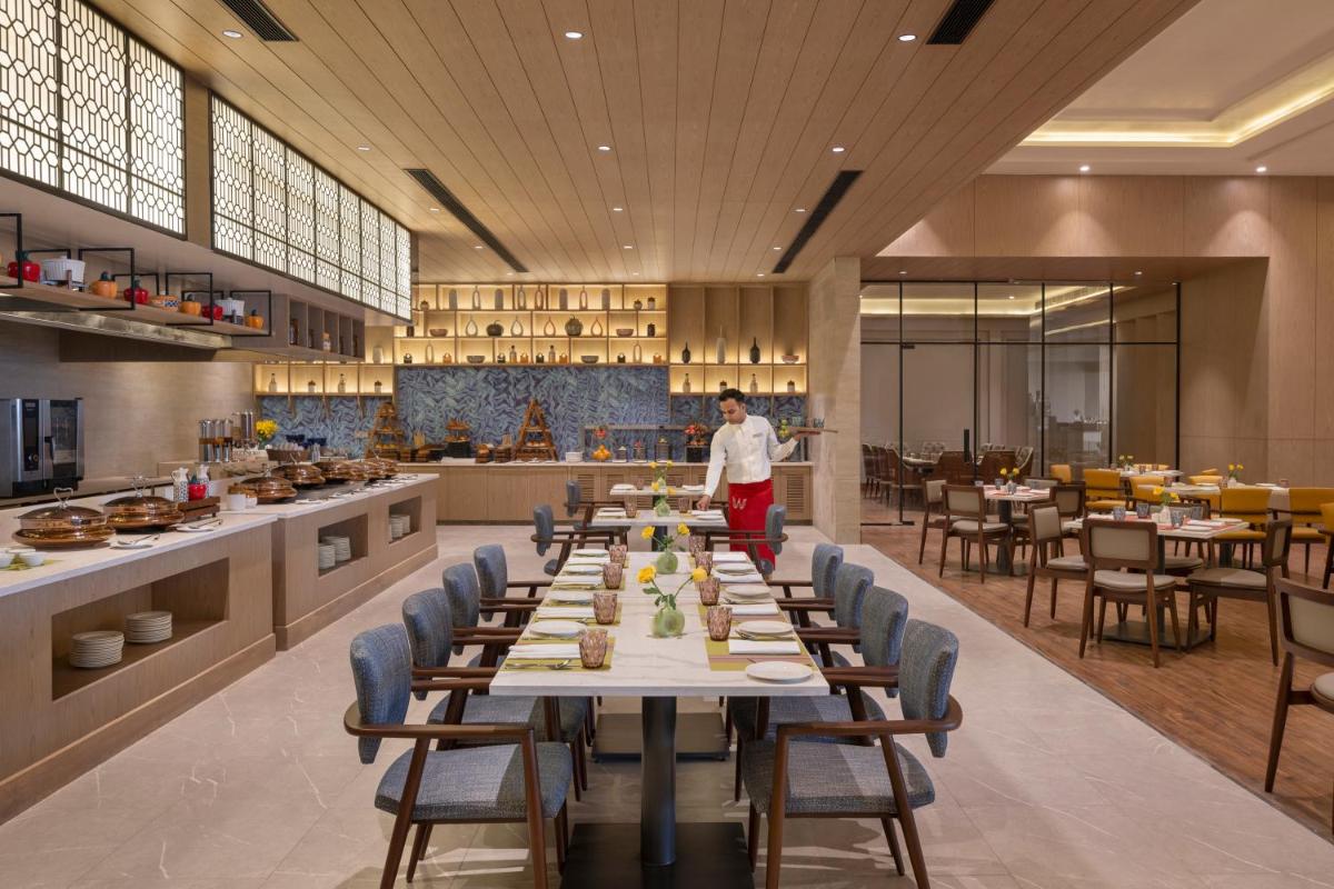 a man standing in a restaurant with a long table at Welcomhotel by ITC Hotels, Delhi-Gurugram Highway in New Delhi