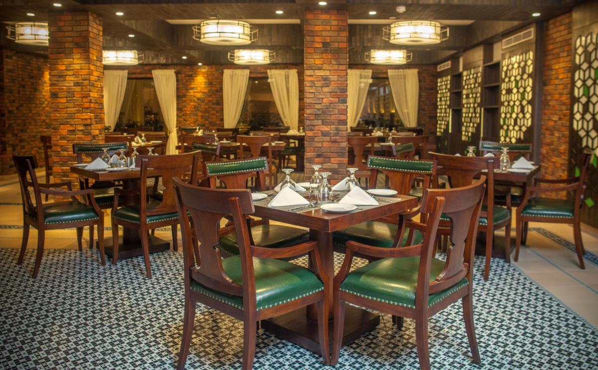 a dining room with wooden tables and chairs at Fragrant Nature Kochi - A Five star Classified Hotel in Cochin