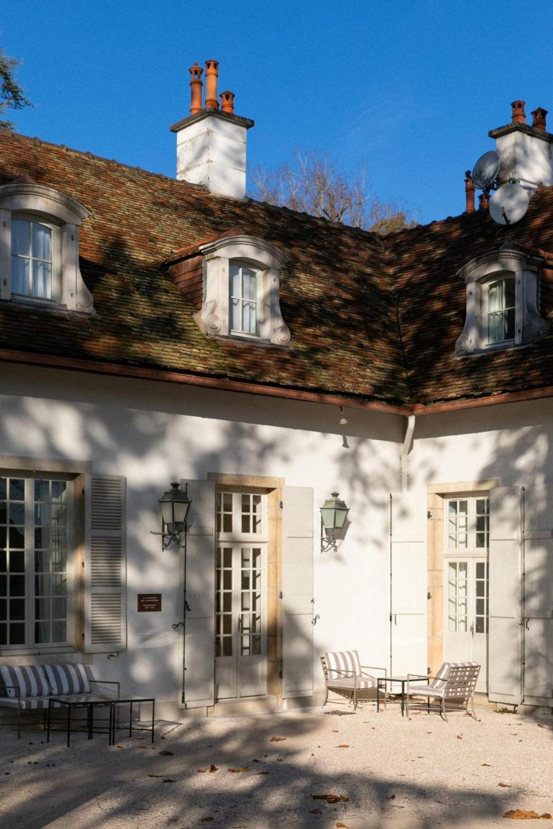 un bâtiment blanc avec des bancs devant dans l'établissement Bellevigne Bourgogne, à Chambolle-Musigny
