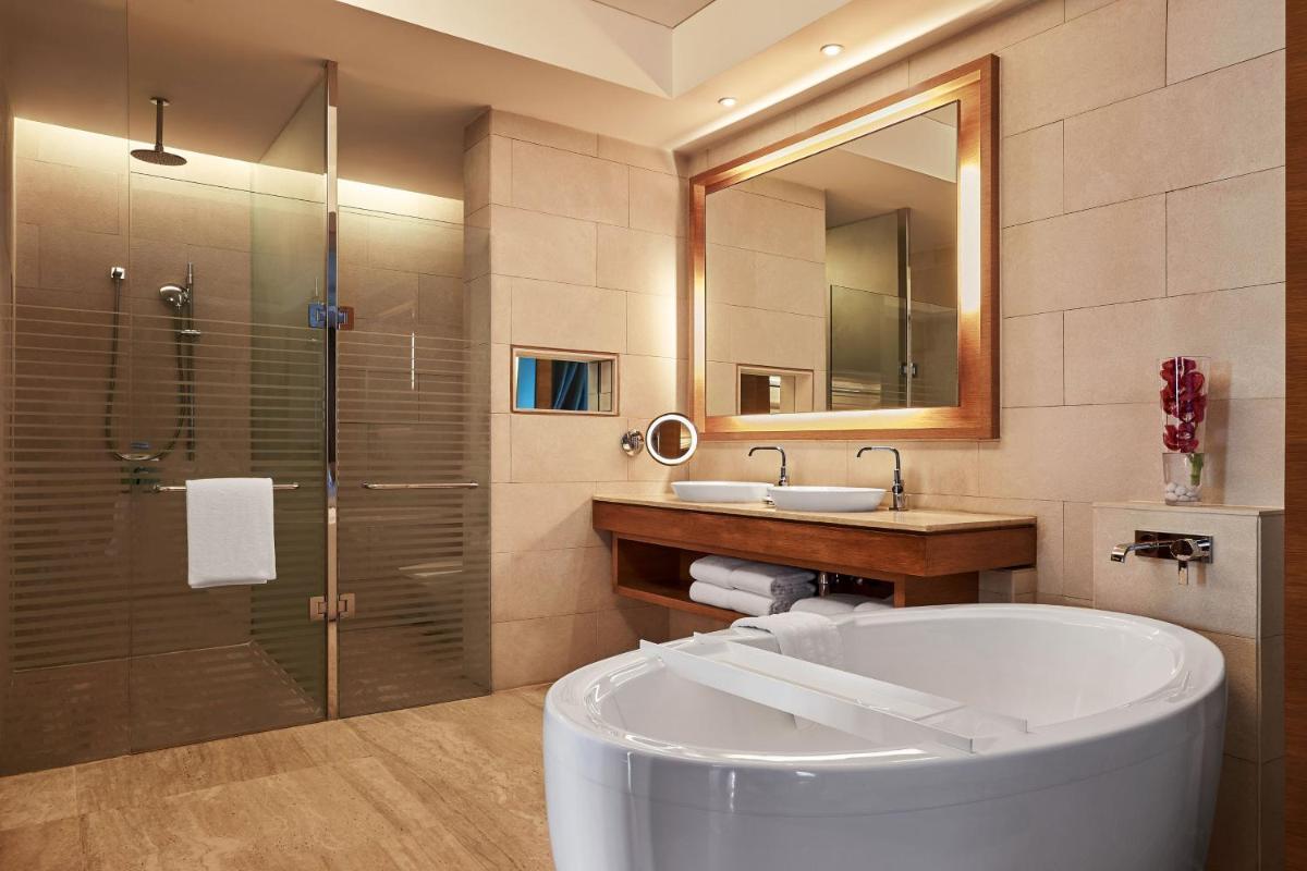 a bathroom with a tub and a shower and a sink at The Westin Mumbai Garden City in Mumbai