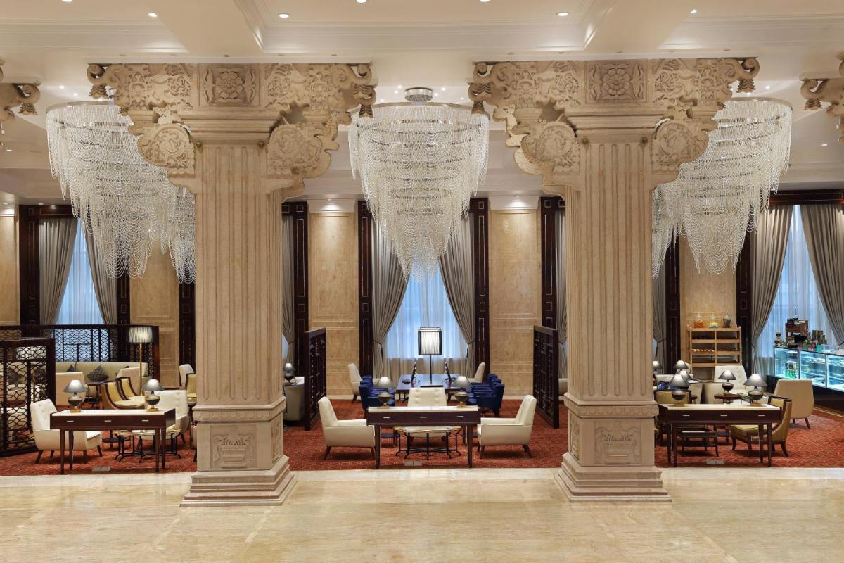 a lobby with columns and chandeliers in a building at Sheraton Grand Pune Bund Garden Hotel in Pune