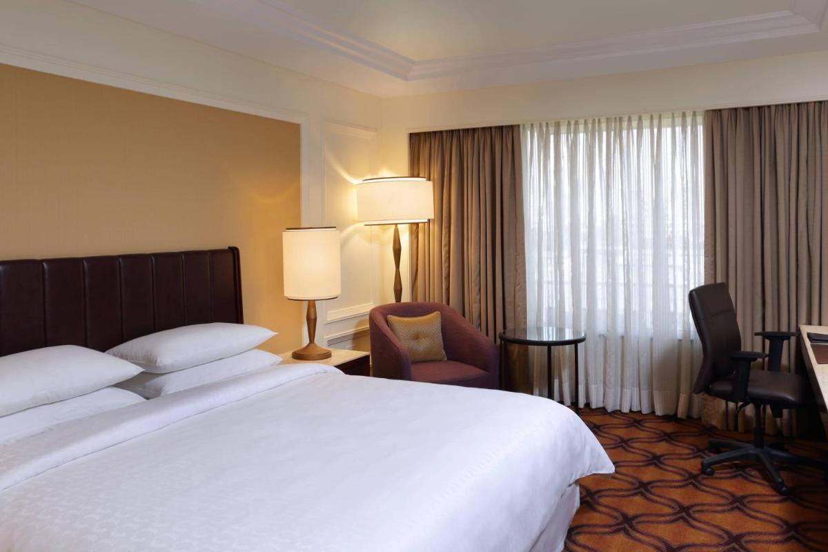 a hotel room with a large bed and a chair at Sheraton Grand Pune Bund Garden Hotel in Pune